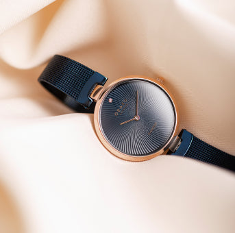 A genuine diamond blue watch with unique waves pattern on the dial against a beige background