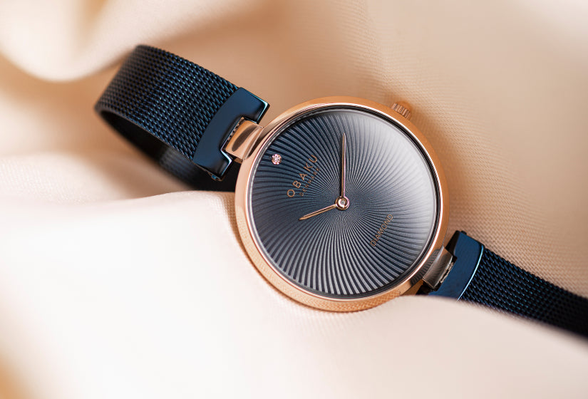 A genuine diamond blue watch with unique waves pattern on the dial against a beige background